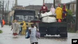 Residentes cruzan una calle inundada, en Batabanó, tras el paso de Idalia por el occidente cubano en 2023.