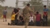 La inmigrante cubana Magdalena Ávila (arrodillada a la izquierda) y otras personas se emocionan después de cruzar ilegalmente la frontera sur de EEUU, el 9 de octubre de 2022 en Eagle Pass, Texas. (Allison Dinner/AFP).