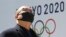 Un hombre se protege del coronavirus frente a un logo de los Juegos de Tokio. AP Photo/Koji Sasahara