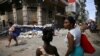 Personas caminan en La Habana entre montones de basura y comercios informales.