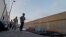 Varias personas que se dirigen a cruzar la frontera pasa delante de varios solicitantes de asilo de Guatemala y Cuba que esperan en un puente a poder entrar en EEUU. (Archivo)